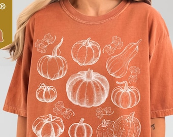 Op de afbeelding: Oranje Comfort Colors T-shirt 1717 met een witte pompoen illustratie. Het shirt heeft een ronde hals en korte mouwen. De tekst "yam" is op het shirt gedrukt. Gemaakt van 100% katoen.