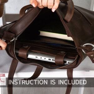 Puede incluir: Un bolso tote de cuero marr&oacute;n con cierre de cremallera y un bolsillo grande en la parte delantera. El bolso est&aacute; abierto y se puede ver un port&aacute;til y un libro en su interior. El texto "INSTRUCTION IS INCLUDED" est&aacute; impreso en la parte inferior de la imagen.