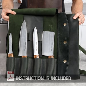 May include: A green leather knife roll with five slots for knives. The roll has a flap that folds over and secures with a snap. The roll is open and shows five knives, including a chef's knife, a paring knife, and a cleaver. The text "INSTRUCTION IS INCLUDED" is printed on the bottom of the roll.
