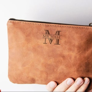 May include: A brown leather zippered pouch with a personalized monogram that reads "MICHAEL M".