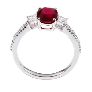 K&ouml;nnte beinhalten: Ein silberner Ring mit einem gro&szlig;en roten Edelstein und zwei kleineren klaren Edelsteinen auf der Ringschiene. Die Ringschiene ist mit kleinen klaren Edelsteinen besetzt.
