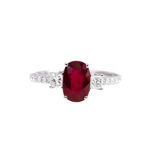 K&ouml;nnte beinhalten: Ein silberner Ring mit einem gro&szlig;en ovalen Rubin, der von kleineren Diamanten umgeben ist.