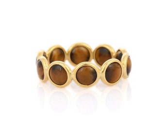 May include: A gold ring with a band of round, brown tiger's eye stones.