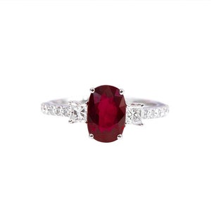 K&ouml;nnte beinhalten: Ein silberner Ring mit einem gro&szlig;en ovalen Rubin, der von kleineren Diamanten umgeben ist.