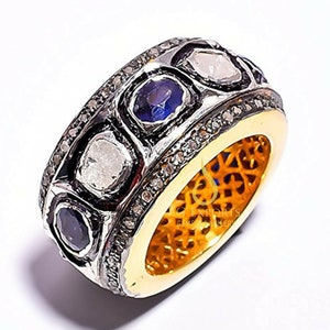May include: A silver and gold ring with a row of blue sapphires and white diamonds. The ring is set in a gold band with a textured design.