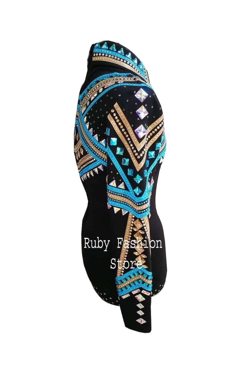 Op de afbeelding: Een zwart shirt met lange mouwen voorzien van ingewikkelde patronen van turquoise, gouden en iriserende kristallen in geometrische vormen over de schouder en mouw. De tekst Ruby Fashion Store is in het wit op de zijkant van het kledingstuk gedrukt.