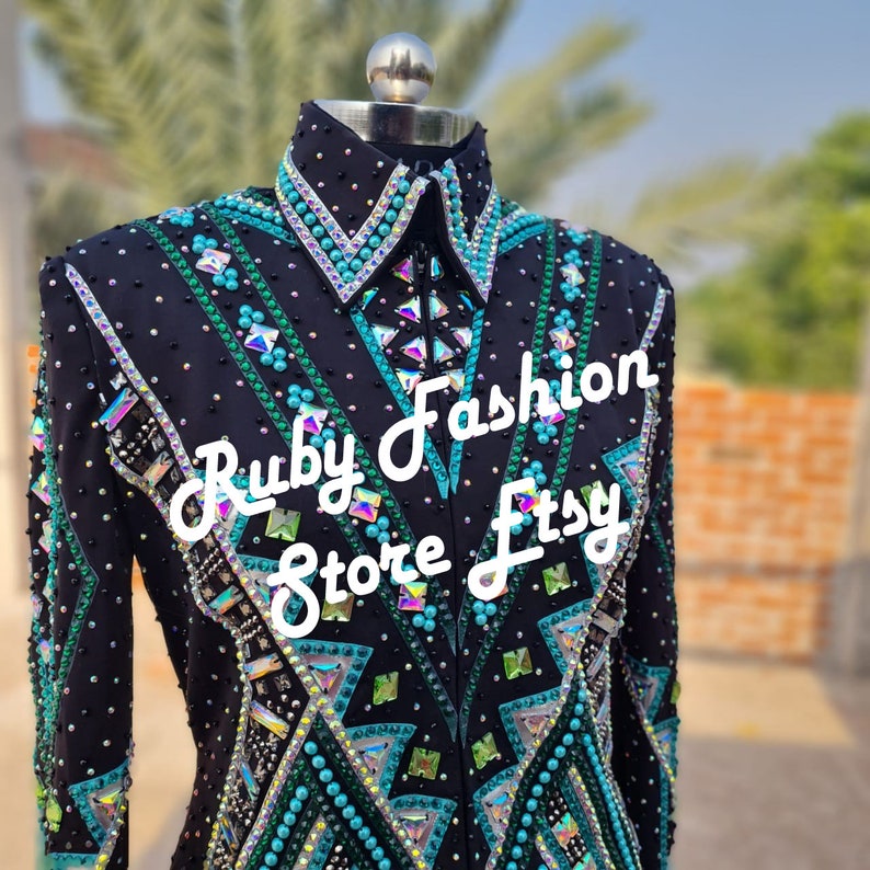 May include: A black long-sleeve shirt featuring a high collar, a front zipper, and intricate geometric patterns in turquoise, green, and silver. The garment is heavily embellished with numerous crystals and beads. Text reads: Ruby Fashion Store Etsy.