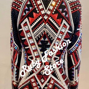 May include: A long-sleeved jacket featuring a black base with intricate red and white geometric patterns, heavily embellished with silver studs, clear crystals, and metallic chains. The text "Red on Black Base" and "Ruby Fashion Store" is visible.