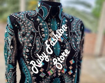 May include: A black long-sleeve shirt featuring a high collar and a front zipper, heavily embellished with intricate patterns of turquoise, silver, and clear crystals. The text Ruby Fashion Store is printed diagonally across the front.