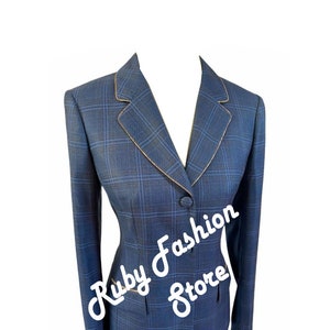 May include: A blue and black checked blazer with a gold trim. The blazer has a single button fastening and a pocket on the left side. The text "Ruby Fashion Store" is visible on the blazer.
