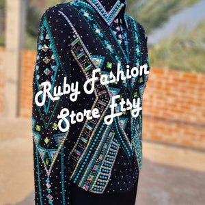 May include: A black long-sleeve jacket featuring intricate geometric patterns in teal, green, and silver. The garment is heavily embellished with various shapes of crystals, beads, and rhinestones. The text Ruby Fashion Store Etsy is overlaid.