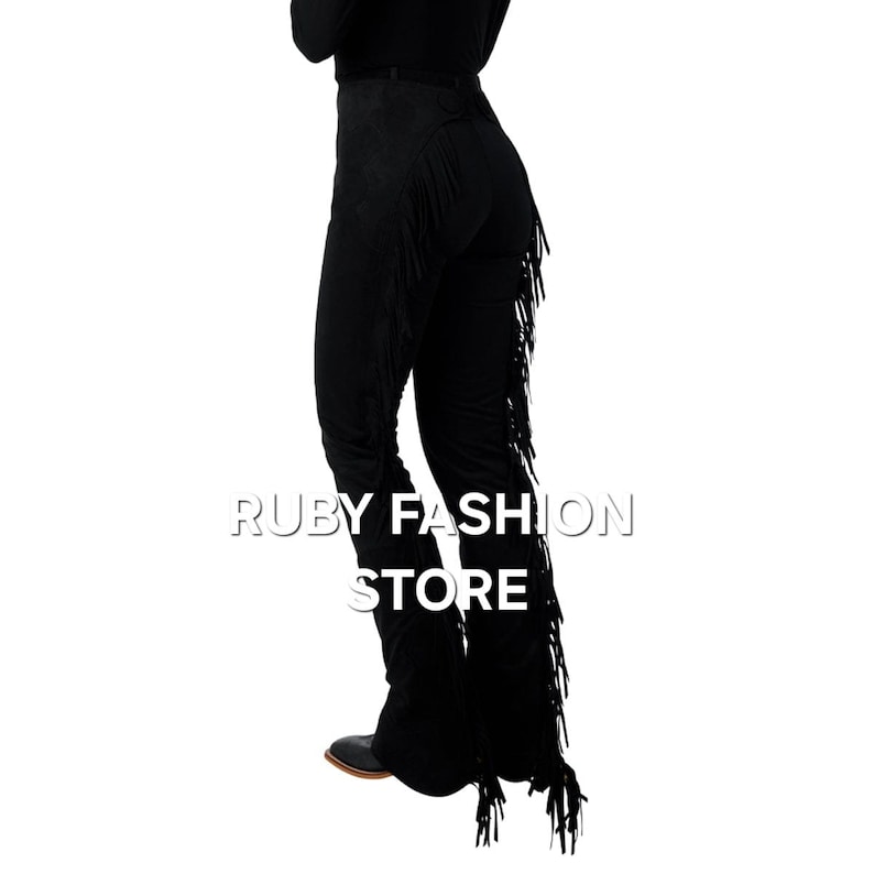 May include: Black suede pants with fringe detail on the sides. The pants are fitted through the hips and legs and have a wide leg opening. The fringe is long and flowing, and the pants are a stylish and unique piece of clothing.