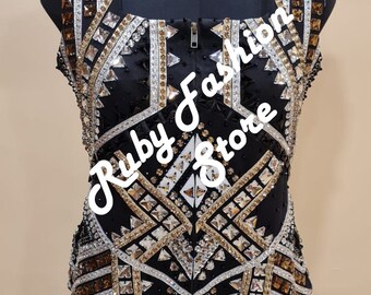Könnte beinhalten: Ein schwarzes ärmelloses Oberteil mit Frontreißverschluss und komplexen geometrischen Mustern, verziert mit silbernen, goldenen und braunen Kristallen und Perlen. Das Kleidungsstück zeigt den Text Ruby Fashion Store in weißer Schreibschrift.