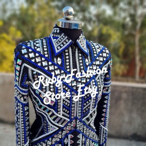 May include: A black show jacket with a geometric design featuring blue and white rhinestones. The jacket has a zipper closure and long sleeves. The text "Ruby Fashion Store Etsy" is visible on the jacket.