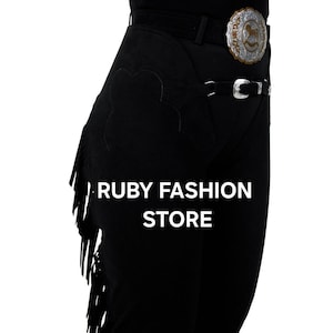 May include: Black leather riding chaps with fringe detail and a silver belt buckle. The chaps have a patch on the left thigh that says "RUBY FASHION STORE".