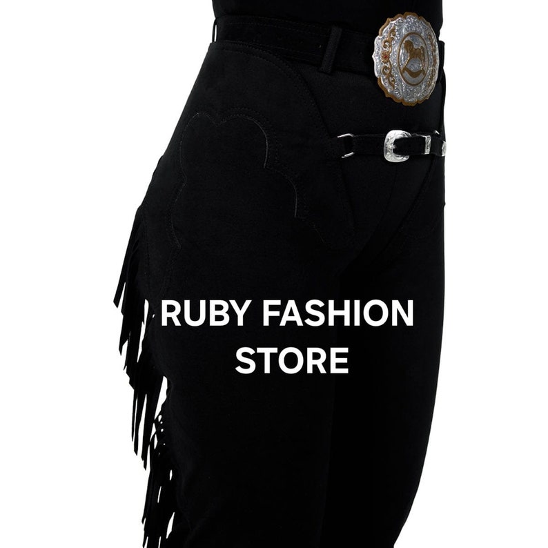 May include: Black leather riding chaps with fringe detail and a silver belt buckle. The chaps have a patch on the left thigh that says "RUBY FASHION STORE".