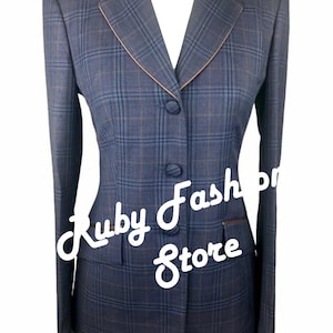 May include: A blue and brown plaid riding jacket with a black velvet collar and a pink trim. The jacket has a single breasted closure with four buttons.