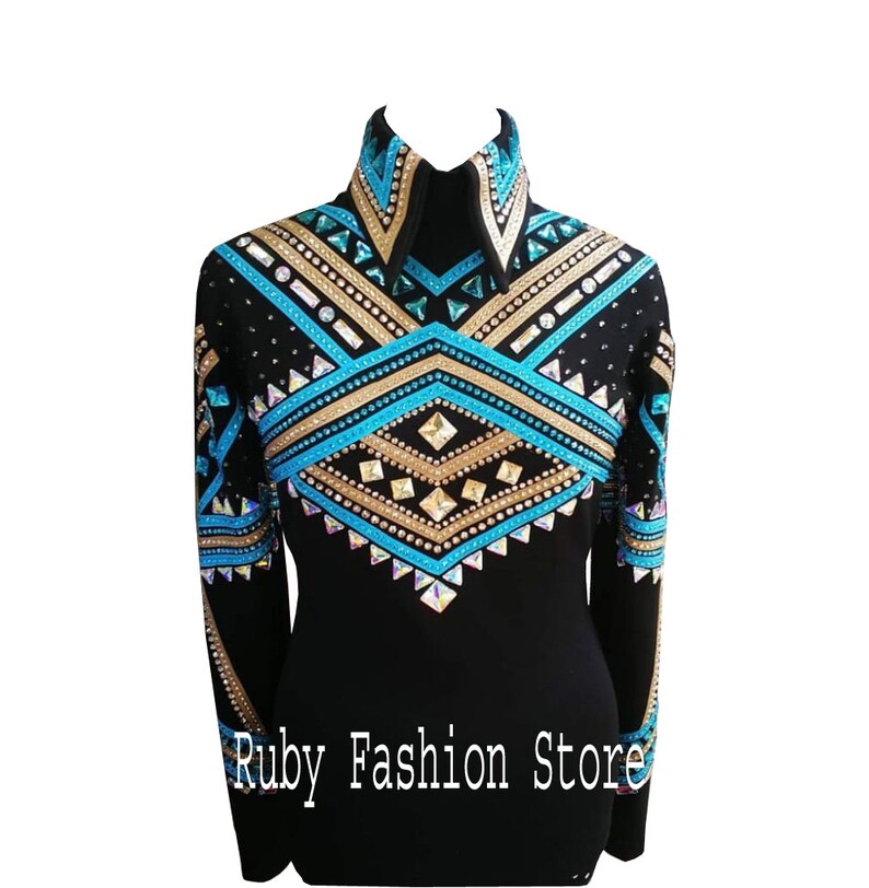 Op de afbeelding: Een zwart shirt met lange mouwen, een hoge kraag en een ingewikkeld geometrisch patroon op de borst en mouwen, versierd met turquoise, gouden en heldere kristallen. De tekst Ruby Fashion Store staat onderaan afgedrukt.