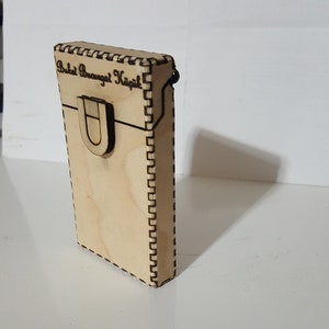 Puede incluir: Una caja de madera con un cierre y el texto "Buket Brougbt Kızık!" grabado en la parte delantera.