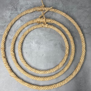 May include: Three concentric circles made of natural brown rope, creating a decorative wreath or wall hanging.