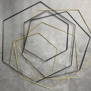 May include: A set of five geometric shapes, four black and one gold, are arranged in a concentric pattern. The shapes are all octagons, with the gold octagon in the center.