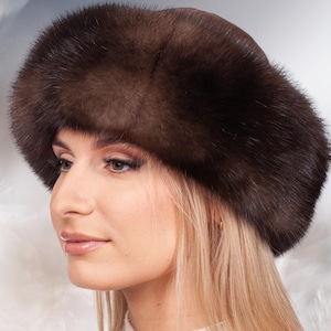 Puede incluir: Un gorro de piel marrón con un ala ancha. El gorro está hecho de piel suave y lujosa y tiene un diseño clásico.