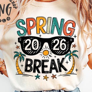 May include: Cream-colored t-shirt with a colorful graphic design. The design features the words "SPRING BREAK 2026" in various colors, sunglasses, palm trees, a sun, and stars. The shirt is paired with blue jeans.