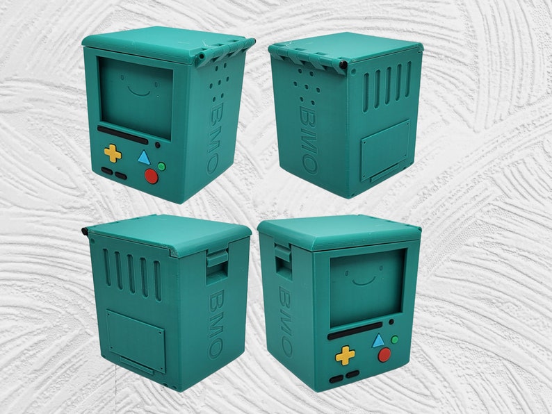 May include: Four teal blue 3D printed boxes with the text "BMO" on the side. Each box has a different design on the front, including a smiley face, a game controller, and a blank panel.