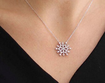 以下が含まれることがあります： キラキラと輝く白い石でできた雪の結晶のペンダントがついた、銀色のチェーンネックレスです。