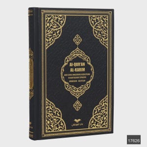 Op de afbeelding: Een zwart hardcover boek met gouden decoratieve patronen. De titel "AI-QUR'AN AL-KARIM" is zichtbaar, samen met tekst in het Duits en Arabisch. Het boek staat rechtop.