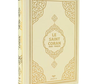 May include: A cream-colored book with gold lettering and intricate gold designs on the cover. The title is "Le Saint Coran" in French, with the words "Arabe - Francais" underneath. The book is a Quran, a holy book in Islam.
