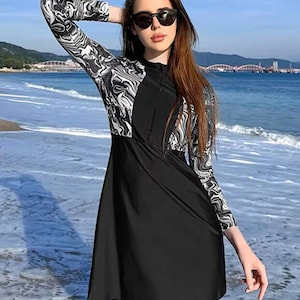 long sleeve swim dress Cagola Swimsuits for Women UPF 50+ Swimwear One Piece Bathing Suit with Skirts Rash Guard Over 50 Black X-Small at Amazon Women's Clothing store a flattering curved hem that dips slightly in the back Sabbia - Long-Sleeve Two-Tone Cut-Out