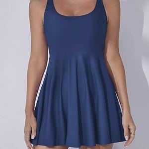 May include: A navy blue athletic dress with a scoop neckline and a flared skirt. The sleeveless dress has a racerback design and is made of a smooth, solid fabric. The dress is suitable for various activities.