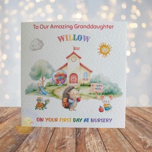 May include: A square greeting card featuring a watercolour illustration of a schoolhouse, a hedgehog with a backpack, a turtle with books, and a mouse. The text reads To Our Amazing Granddaughter, WILLOW, and ON YOUR FIRST DAY AT NURSERY.