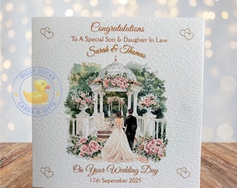Puede incluir: Tarjeta de boda con una ilustración en acuarela de una pareja caminando hacia un cenador adornado con flores. La tarjeta dice: "Felicitaciones a un hijo y nuera especiales, Sarah y Thomas" y "En el día de tu boda, 17 de septiembre de 2025".