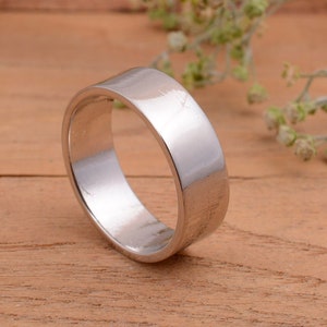 Puede incluir: Un anillo de banda de plata simple con un acabado liso y pulido.