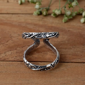 Op de afbeelding: Zilveren ring met een bloemenmotief. De ring is aan één kant open en heeft een dubbele band.