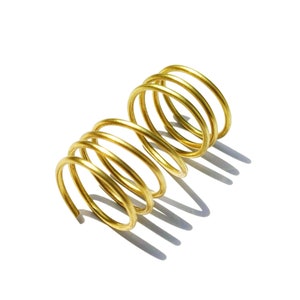 May include: A gold-colored metal spring coil with multiple loops.