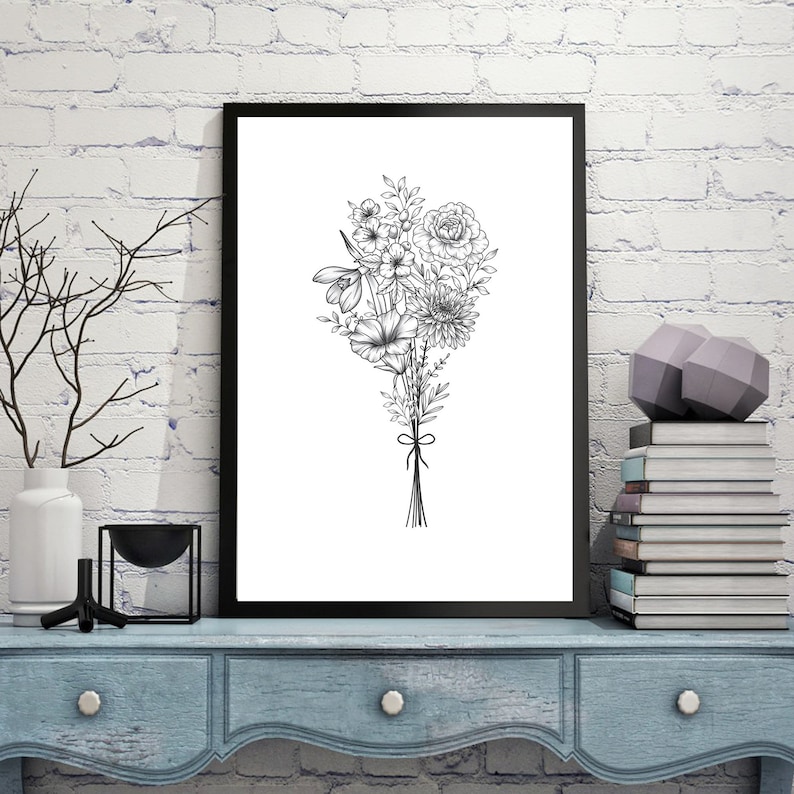 May include: A black and white line drawing of a bouquet of flowers in a black frame. The flowers are tied together with a ribbon. The frame is hanging on a white brick wall.