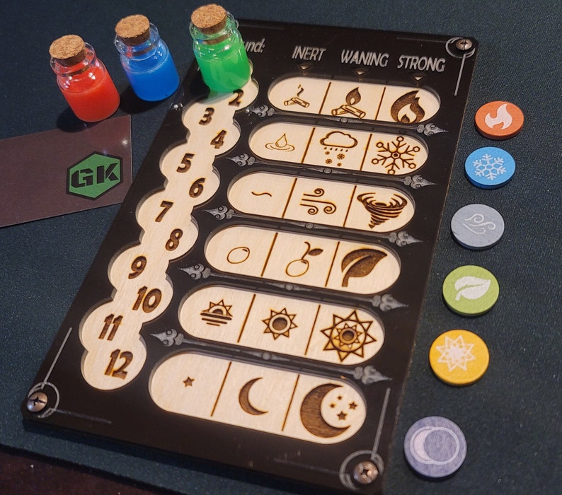 May include: A black and wood-toned game board with etched symbols and numbers, alongside colorful tokens and small glass bottles filled with red, blue, and green liquids. The board has the text "INERT WANING STRONG".
