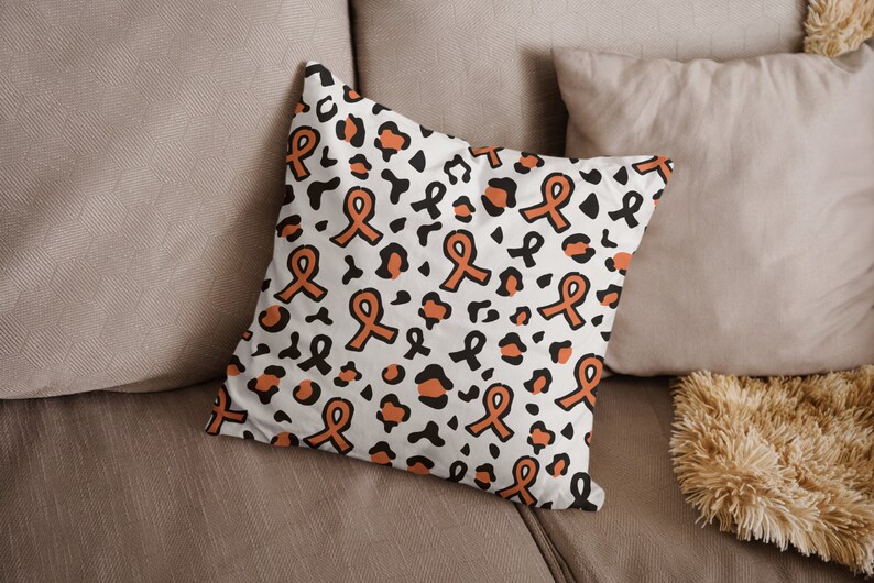 May include: A white cushion with a pattern of orange awareness ribbons and black leopard spots.
