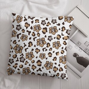 May include: A white pillow with a brown and tan leopard print and brown hibiscus flowers.