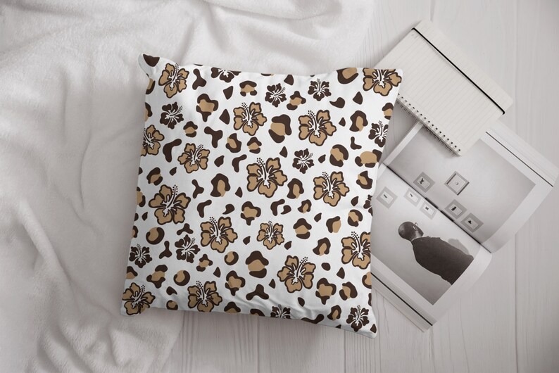 May include: A white pillow with a brown and tan leopard print and brown hibiscus flowers.