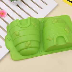 May include: Green silicone mold shaped like two beehives. The mold is designed to make honeycomb-shaped treats.