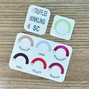 May include: A collection of three white sticker sheets featuring various circular and rectangular designs. The labels include text such as TRUFFLES, INKLING, SC, NIGHT LIGHT, CRISP, ROSEBERRY, TWIG, ESTATE, and VARIETAL, accompanied by icons.