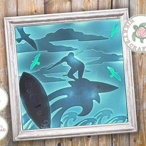 May include: A digital download of a silhouette design of a surfer riding a wave with seagulls flying overhead. The design is in shades of blue and green, with a black surfboard and a black silhouette of the surfer. The design is framed in a white frame.