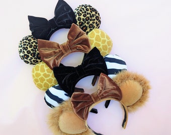 May include: A set of four pairs of mouse ears with different animal print fabrics. The ears are brown, black, and tan with a variety of animal prints, including leopard, zebra, and giraffe.