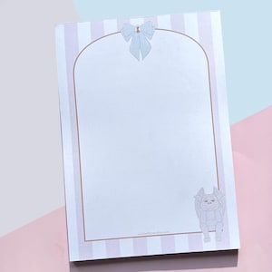 May include: A notepad with a light blue and pink striped border. A light blue bow adorns the top, and a cartoon gargoyle is at the bottom. The notepad features a blank, arched interior.
