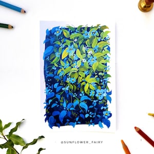 May include: A painting of a vibrant floral arrangement featuring blue and green leaves and small blue flowers. The artwork is on white paper, with colored pencils and a sprig of greenery around it. The artist's name, @SUNFLOWER_FAIRY, is at the bottom.