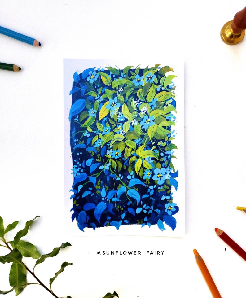 May include: A painting of a vibrant floral arrangement featuring blue and green leaves and small blue flowers. The artwork is on white paper, with colored pencils and a sprig of greenery around it. The artist's name, @SUNFLOWER_FAIRY, is at the bottom.